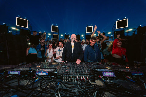 Festival techno en Égypte - DJ aux platines Sandbox et public au crépuscule